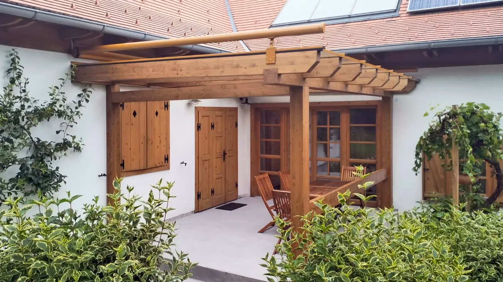 Fa pergola egy udvari terasz fölött, részben elkészült tetőszerkezettel