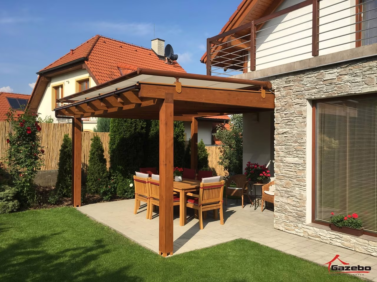 Fenix fa pergola burkolt terasz fölött étkezőgarnitúrával kőburkolatú ház mellett